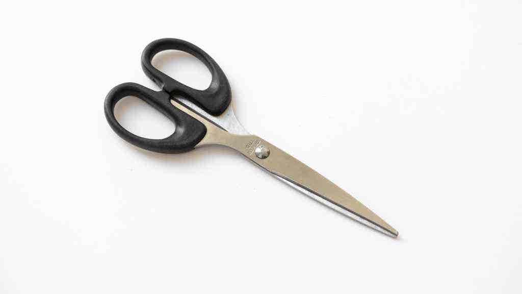 Photo of scissors with a black handle on white background